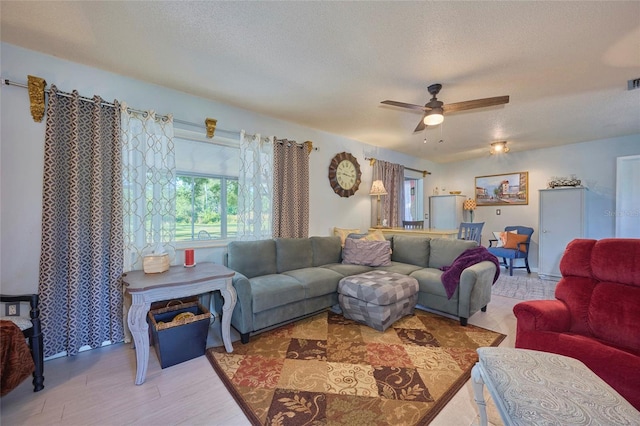 living room with ceiling fan and a textured ceiling