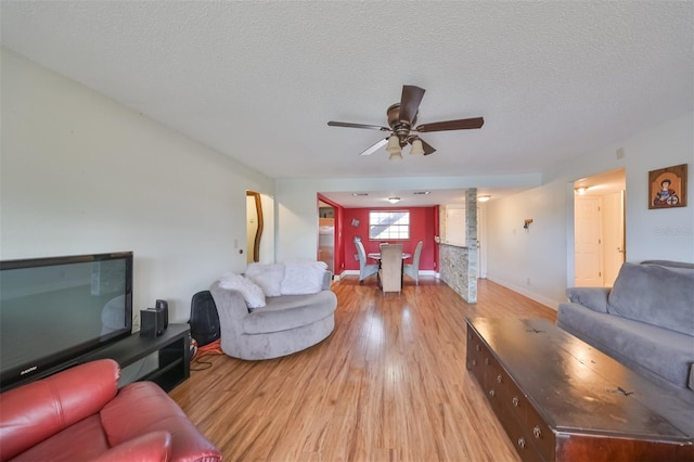 living room with hardwood / wood-style flooring, ceiling fan, and a textured ceiling