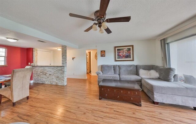 living room featuring light hardwood / wood-style floors, a textured ceiling, and ceiling fan