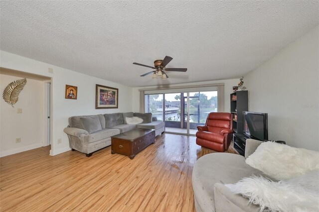 living room with ceiling fan, light hardwood / wood-style flooring, and a textured ceiling