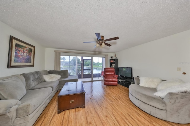 living room featuring ceiling fan, a textured ceiling, and light wood-type flooring