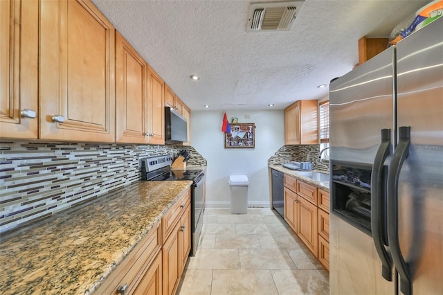 kitchen with sink, a textured ceiling, stone counters, appliances with stainless steel finishes, and decorative backsplash