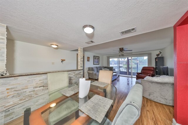 dining room with hardwood / wood-style floors, ceiling fan, and a textured ceiling