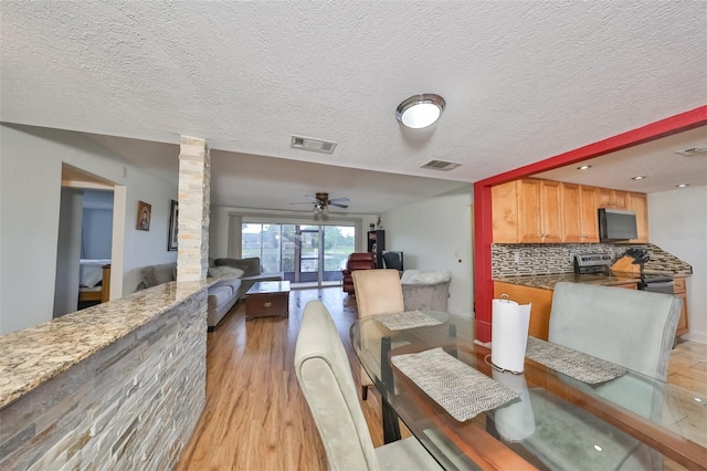 dining room with ceiling fan, light hardwood / wood-style floors, and a textured ceiling