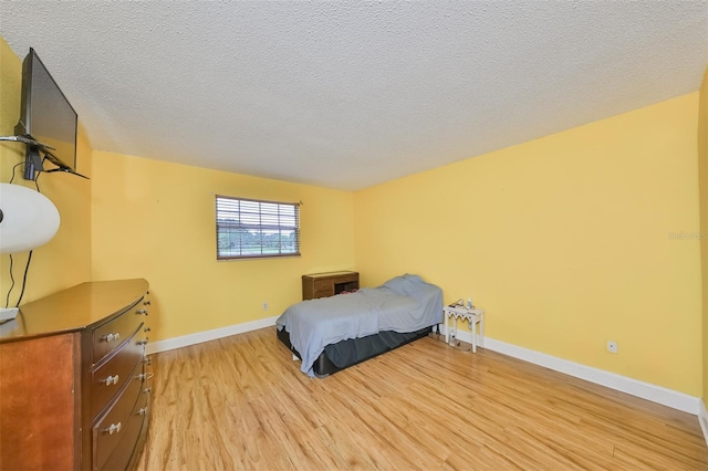 bedroom with light hardwood / wood-style floors and a textured ceiling