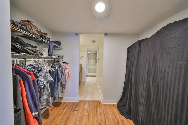 walk in closet with light hardwood / wood-style flooring