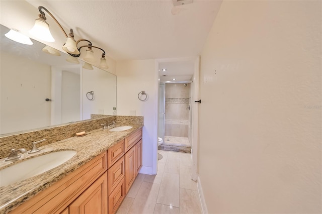 bathroom with double sink, tile floors, an enclosed shower, vanity with extensive cabinet space, and toilet