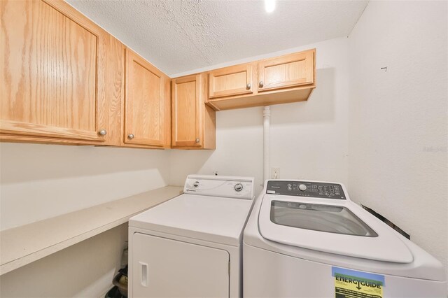 washroom featuring washer and clothes dryer, cabinets, and a textured ceiling