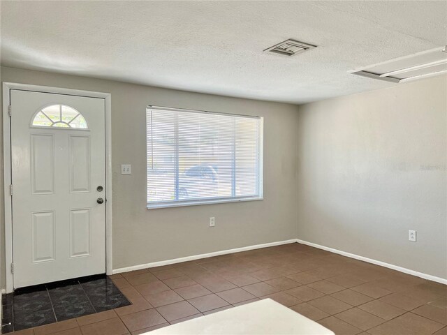 entryway with a textured ceiling and dark tile patterned flooring