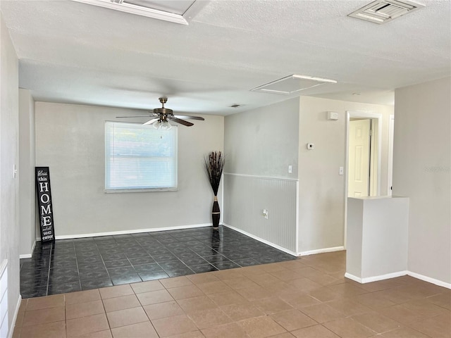 empty room featuring dark tile patterned floors, a textured ceiling, and ceiling fan