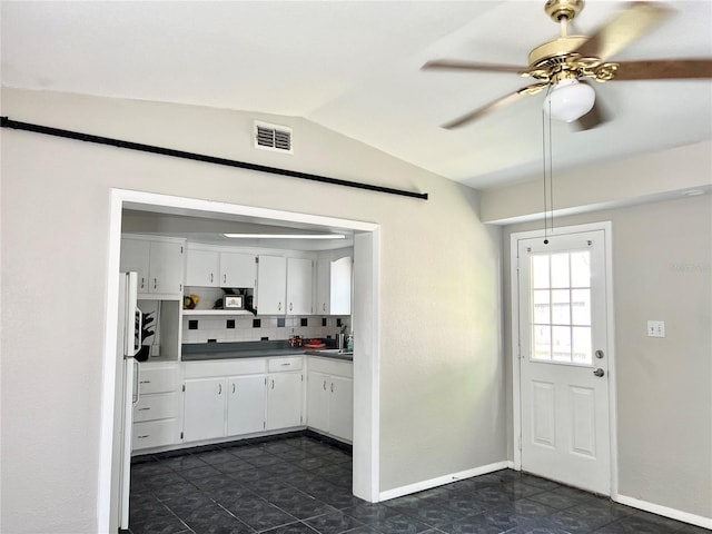 kitchen with decorative backsplash, ceiling fan, white cabinetry, vaulted ceiling, and dark tile patterned flooring