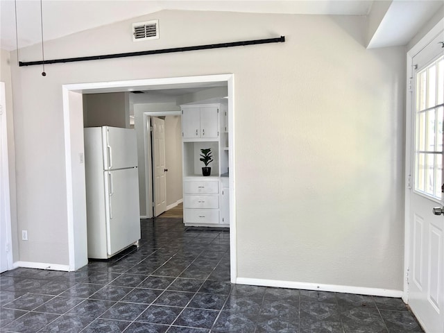 kitchen featuring vaulted ceiling, white cabinetry, and white refrigerator