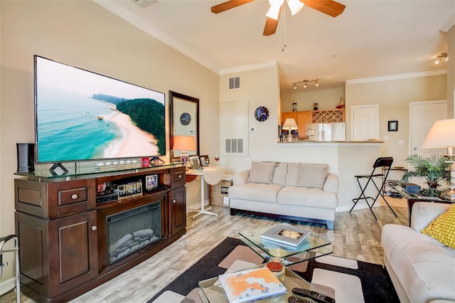 living room with ornamental molding, light hardwood / wood-style floors, and ceiling fan