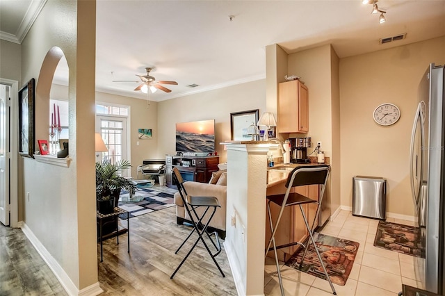 interior space featuring rail lighting, ceiling fan, light wood-type flooring, and ornamental molding