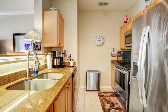 kitchen with appliances with stainless steel finishes, light stone counters, sink, light tile floors, and ornamental molding