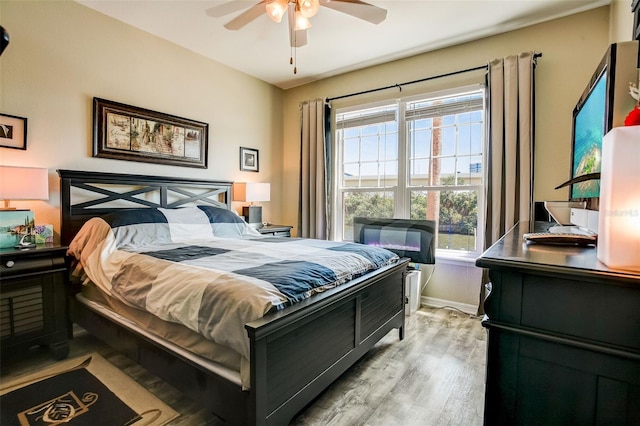 bedroom featuring baseboards, light wood-style flooring, and a ceiling fan