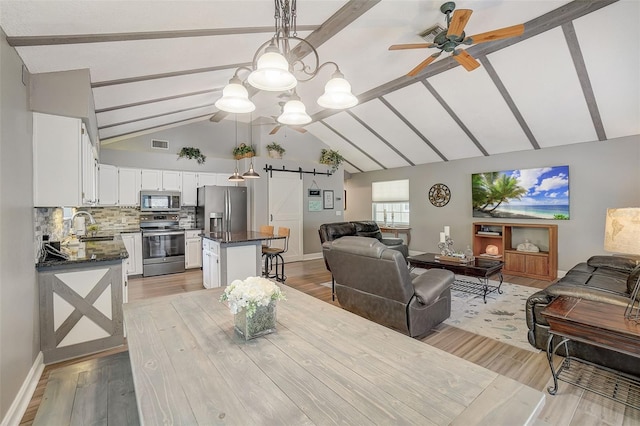 dining area featuring beamed ceiling, sink, ceiling fan, and light wood-type flooring