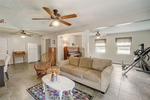 tiled living room featuring ceiling fan and a textured ceiling