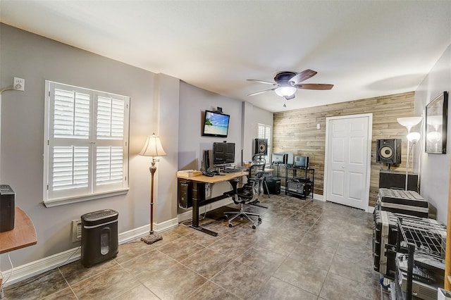 tiled home office featuring ceiling fan and wood walls