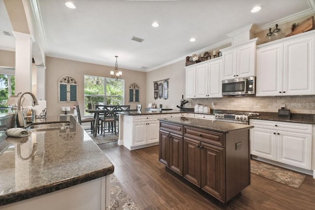 kitchen featuring stainless steel appliances, dark wood-type flooring, an island with sink, white cabinets, and sink