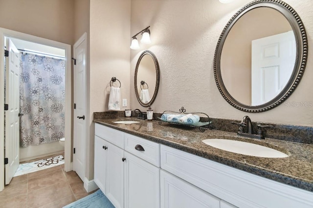 bathroom featuring toilet, tile flooring, and dual vanity