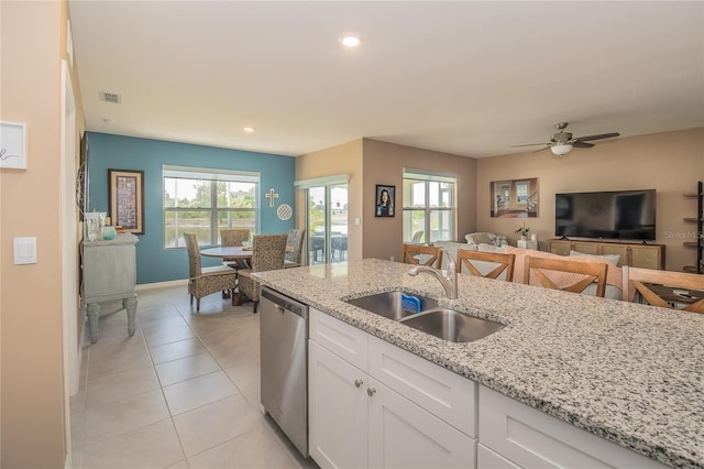 kitchen featuring light stone countertops, light tile floors, sink, dishwasher, and ceiling fan