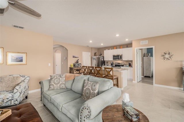 living room featuring ceiling fan, sink, and light tile flooring