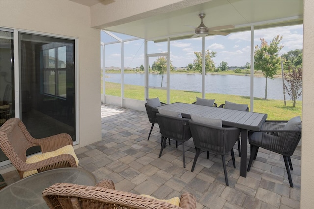 sunroom with ceiling fan and a water view