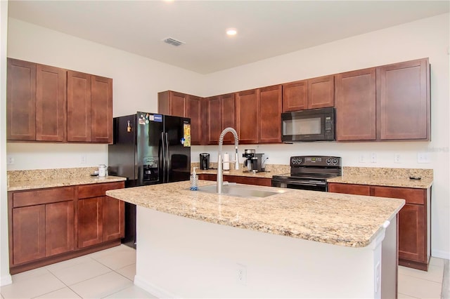 kitchen with light tile patterned floors, black appliances, sink, and an island with sink