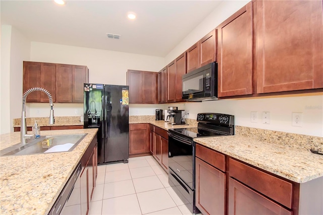 kitchen with light stone countertops, black appliances, sink, and light tile patterned floors