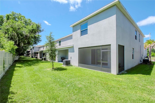 back of property featuring a sunroom, a lawn, and cooling unit