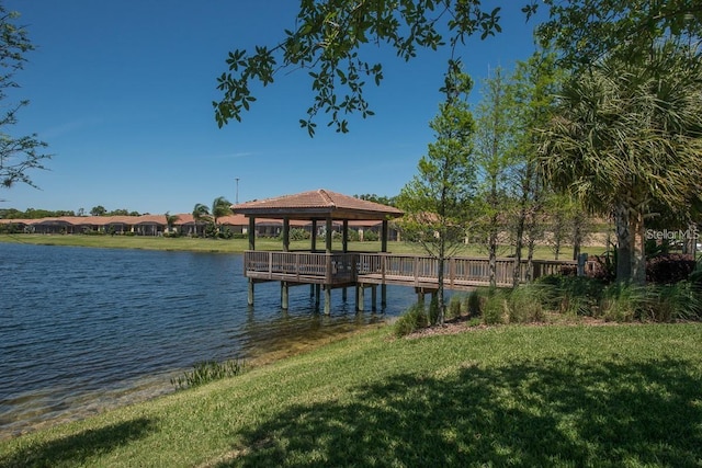 dock area with a gazebo, a yard, and a water view