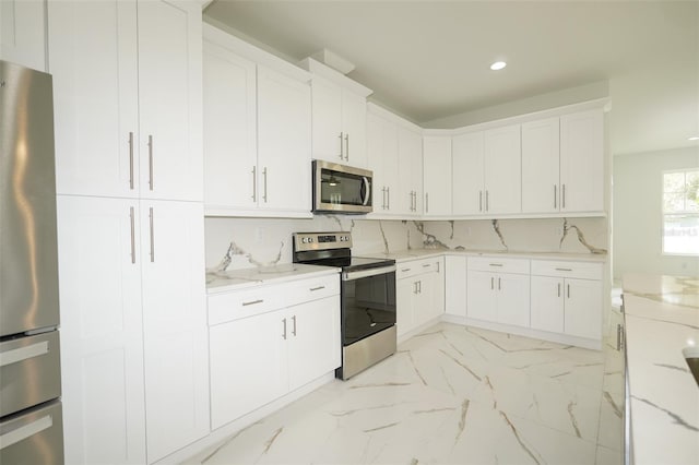 kitchen featuring tasteful backsplash, light stone countertops, appliances with stainless steel finishes, and white cabinets