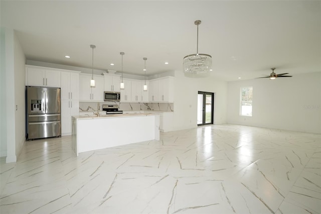 kitchen with white cabinets, stainless steel appliances, hanging light fixtures, and backsplash