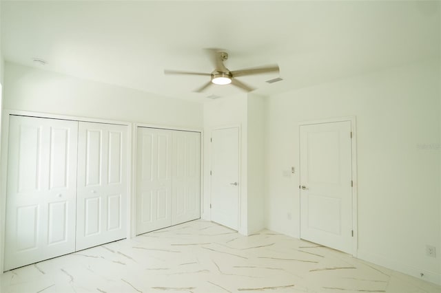 unfurnished bedroom with ceiling fan and multiple closets