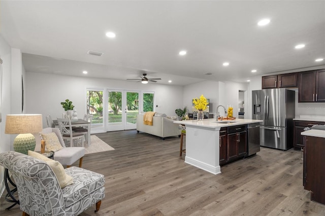 kitchen with an island with sink, appliances with stainless steel finishes, a kitchen breakfast bar, light hardwood / wood-style flooring, and sink