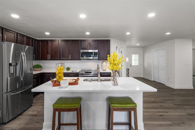 kitchen featuring a kitchen bar, a center island with sink, appliances with stainless steel finishes, dark hardwood / wood-style floors, and sink