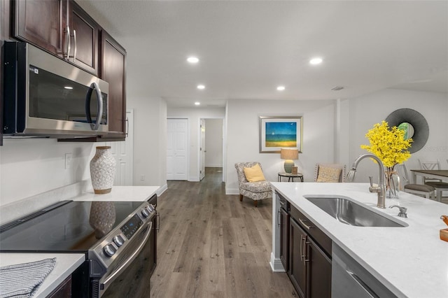 kitchen featuring dark brown cabinets, appliances with stainless steel finishes, light hardwood / wood-style floors, and sink