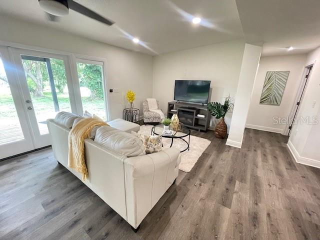 living room featuring ceiling fan and dark hardwood / wood-style floors