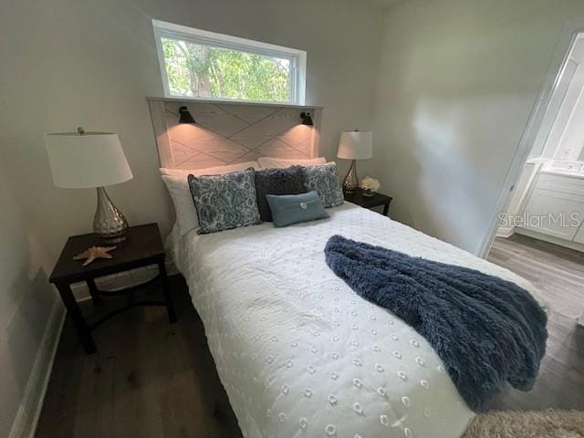 bedroom featuring connected bathroom and hardwood / wood-style flooring