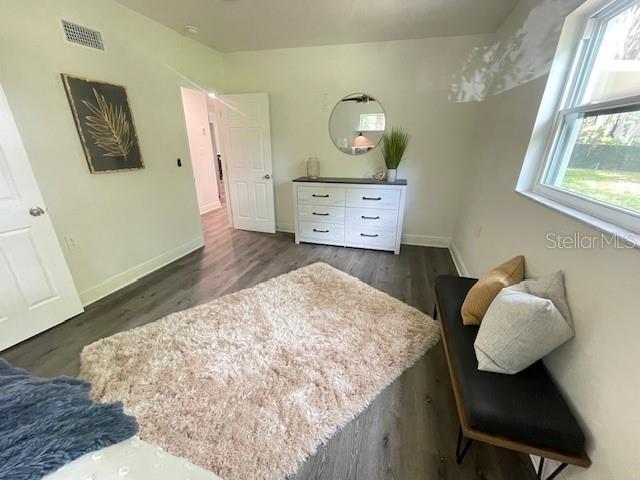 bedroom with multiple windows and dark hardwood / wood-style floors