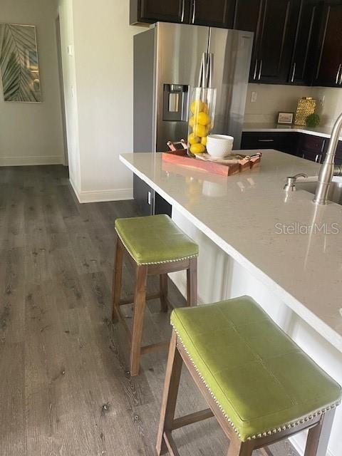 kitchen with a breakfast bar, sink, dark hardwood / wood-style flooring, and stainless steel fridge with ice dispenser