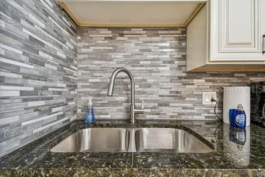 kitchen featuring dark stone countertops, sink, and white cabinets