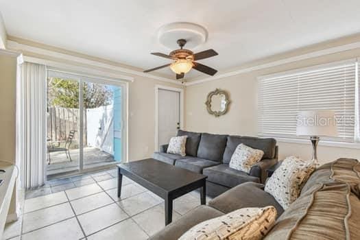 living room featuring crown molding, light tile patterned flooring, and ceiling fan