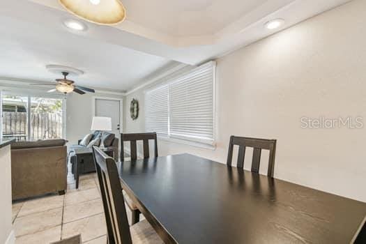 tiled dining room featuring ceiling fan and a tray ceiling