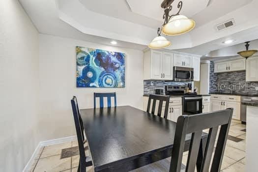 tiled dining room featuring a tray ceiling