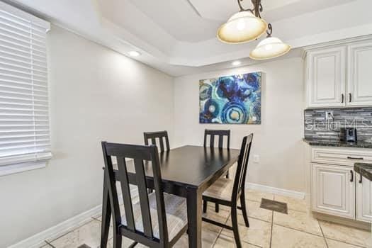 tiled dining room with a raised ceiling