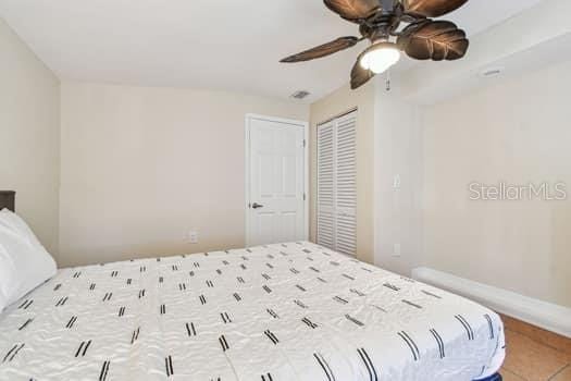 bedroom with tile patterned flooring, a closet, and ceiling fan