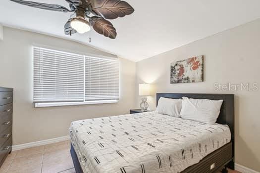 bedroom with lofted ceiling, light tile patterned floors, and ceiling fan