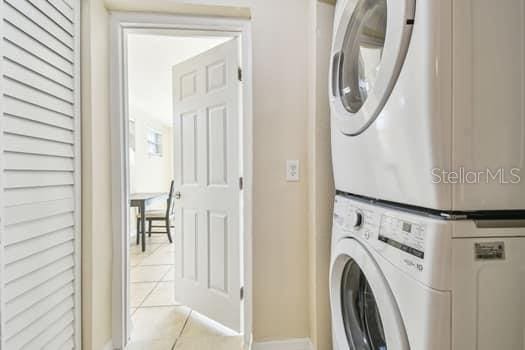 clothes washing area featuring stacked washer / dryer and light tile patterned floors